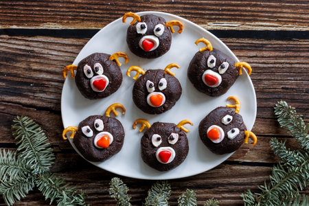 White plate with homemade chocolate Christmas cookies in shape of reinreer head on a wooden table background. Festive food concept. Top view, copy spaceの写真素材