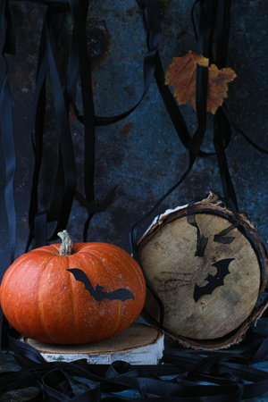 orange pumpkin and black bats and wooden circle looking like moon on dark background. Halloween, vertical, side viewの写真素材
