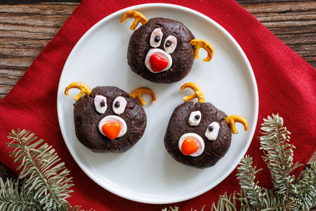 White plate with homemade chocolate Christmas cookies in shape of reinreer head on red napkin on wooden table background. Festive food concept. Top view, close upの写真素材