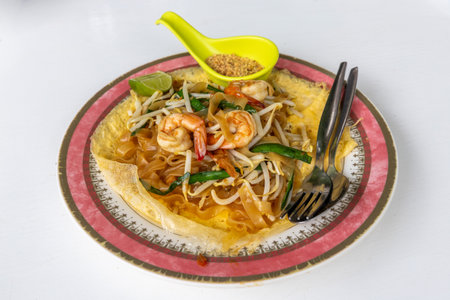 Stir fried rice noodle thai style with shrimps and vegetables Pad Thai kung sod on omelet on white background, food popular with Thai and foreigners. Have a delicious national taste goodの写真素材