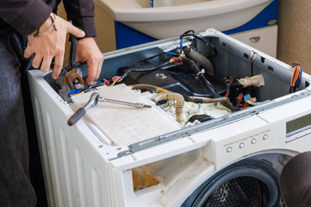 Close up of two repairmen worker s hand working, fixing washing machine using pliers and in the bathroom. Repair service concept.の写真素材