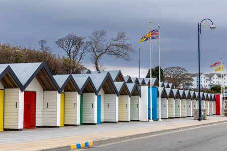 Row of wooden white beach huts with colorful doors in spring in seafront in Swanage, UK. South coast of England, Dorset. No peopleの写真素材