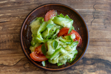 Vegetarian salad with fresh marinated zucchini and tomatoes on wooden table, top viewの写真素材