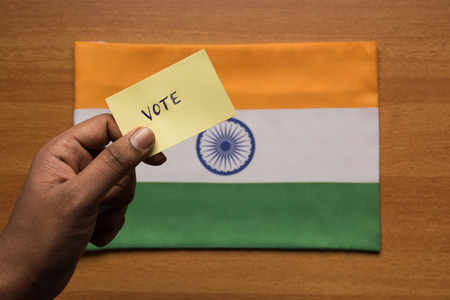 Voting concept - Person holding Hand Written Voting Sticker on India Flag.の写真素材