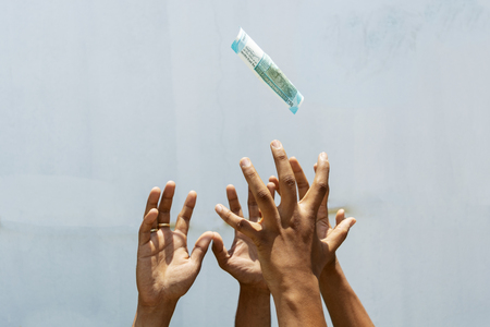 Hands trying to get or catch the flying money on isolated background.の写真素材