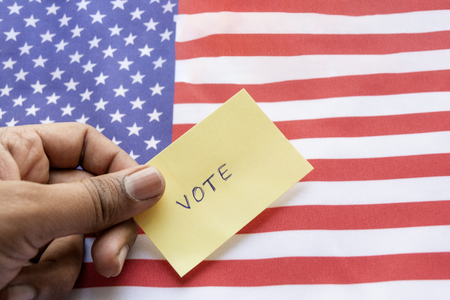 Concept of US election, Vote sticker holding in hand on US flagの写真素材