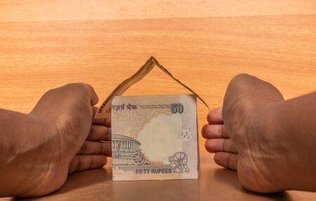 Property insurance concept, Hands protecting the house made with Indian paper currency