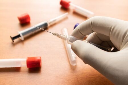 Doctor hand in white glove holding syringe, to get blood sample in laboratory with Plain Clot...