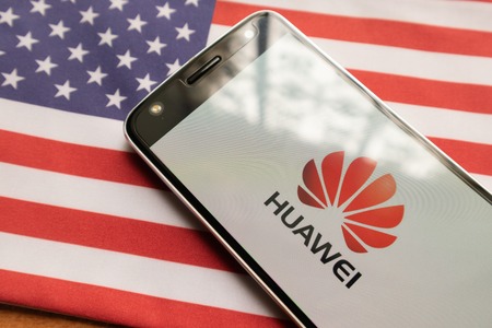 Maski, India - June 21, 2019: Huawei logo on screen of Mobile on US flag.