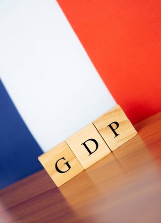 Gross Domestic Product or GDP of France in wooden block letters on table, France flag as a backgroundの写真素材