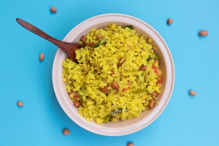 Flat lay of Fresh Poha an Indian snacks on bowl with spoon with peanuts