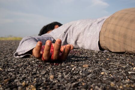 Concept of Crime scene ,Selective focus to victim hand with blood of a dead body laying on Road.