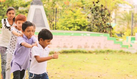 Childrens playing train game at park, outdoor - Boys and girls, plays a train game by holding shoulder of the ahead child - kids playing outside during leisure.の写真素材