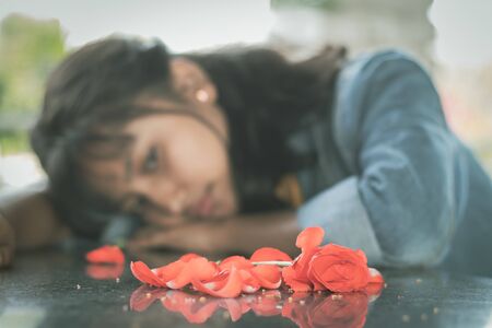 Selective focus on red rose lonely young teenager - concept of love breakup or broken heartの写真素材