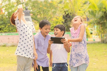 Group of Children laughing by seeing media on mobile - kids having fun by by looking on Smartphone - concept of teens addicted to cellphones and technology.の写真素材