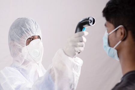 Epidemiologist check fever by digital thermometer at hospital counter for scan and protect from...
