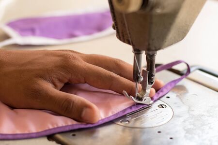 Close up of hands using sewing machine to sew the face medical mask during coronavirus or covid-19...
