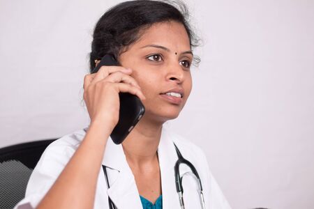 Close up shot of Female doctor talking on mobile phone in her office - concept of telehealth, telehealth service during coronavirus or covid-19 outbreakの写真素材