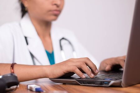 Close-up of doctor hands busy in working on laptop - Online Chat, telehealth, or tele counseling...