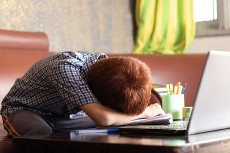 Bored kid slept infront of laptop during remote learning - concept of kid tired from e-learning or online education at home during covid-19 or coronavirus outbreak.の写真素材