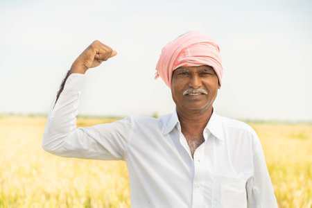 Indian Farmer standing in front of agriculture land and showing strength gesture - concept showing of agricultural farmland is farmers strength.の写真素材