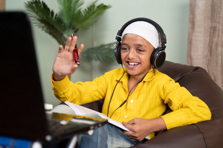 Muslim kid busy on online class by making video call on laptop - concept of new normal, e-learning,...