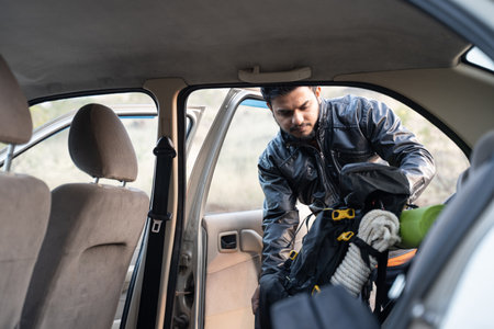 Young man taking out backpack from the car before starting hiking or trekking - concept of solo adventure and travelingの写真素材