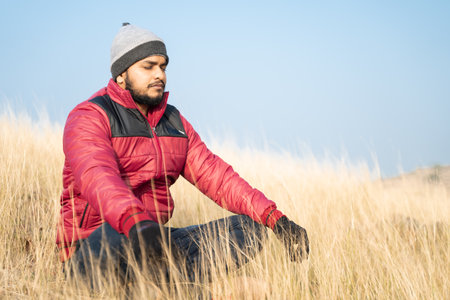 Traveller meditating on top of the mountain during cold morning - Concept of connecting with nature, enlightenment and mindfulnessの写真素材