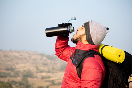 Thirsty travler drinking water by taking break while climbing - Concept of drink water before...