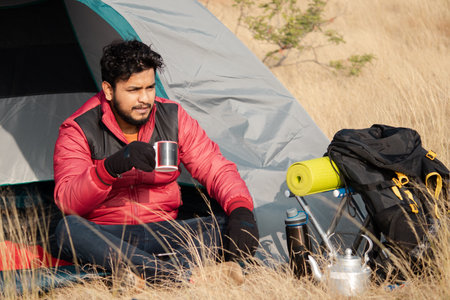 Traveler busy drinking tea or coffee infront of camping tent on top of mountain by looking landscape.の写真素材