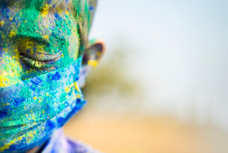 Close up half face head shot of Young boy with medical face mask played holi the festival of colours...