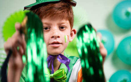 Cheerful happy dancing Young kid with green dress on decorated background - concept of saint...