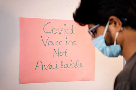 Young Man got worried after looking vaccine not available notice board on hospital doorの写真素材