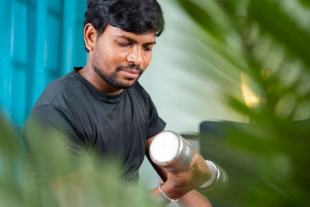 Young man doing exercise using book due virus  pandemic lock down - concept of new normal, home gym,...