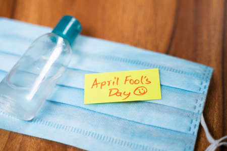April fools day sticky note on Medical face mask with hand sanitizer bottle on table - concept of April fools day celebrations during pandemic.の写真素材