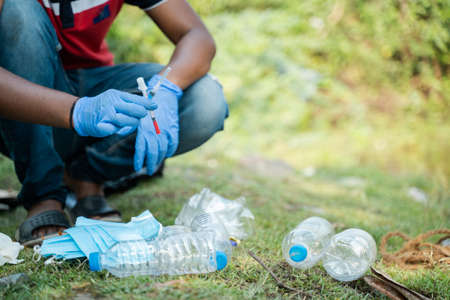 unrecognizable volunteer or waste collector busy sepereating and collecting discarded medical or PPE waste from plastic litter during coronavirus covid-19 pandemicの写真素材