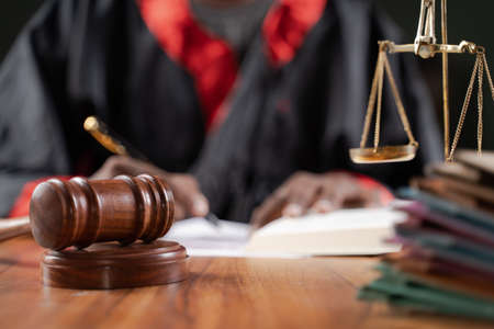 Focus on judge gavel, Unrecognizable judge busy writing verdict or making notes from the book with...