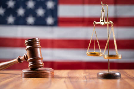 Concept of USA or American justice system showing by using Judge Gavel and Balance scale on US flag...