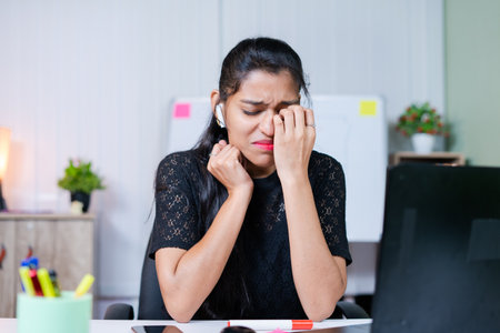 medium shot of frustrated sad crying young indian woman at work place - concept of emotional, mental or work stress at officeの写真素材