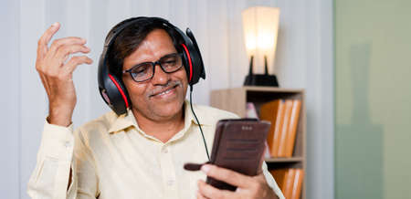 Happy smiling businessman enjoying by listening music in headphones at office - concept of taking break, relaxation while at work.の写真素材