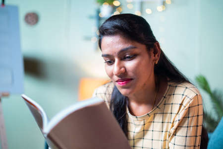 Medium shot of concentrated young girl reading book - concept of leisure activities, preparing for exam, education and learning.の写真素材
