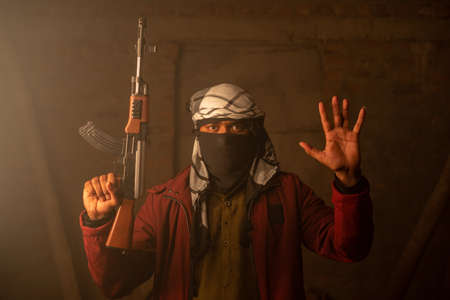 Militant or Gangster with face cover and gun in hand surrendering by putting hands upの写真素材