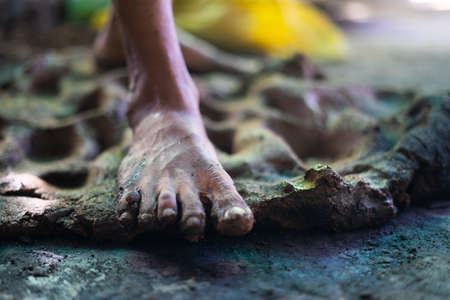 Close up of legs preparing or mixing clay before making pot or earthenware - Traditional way of crushing or wedging the pottery caly to make it bubble freeの写真素材