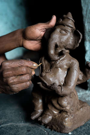 Close up of artist hands making clay ganesh idol for ganesha festival - concpet of religious festival preparations.の写真素材