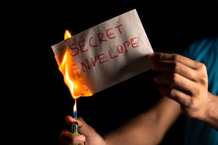 closeup shot of hands burning top-secret document or envelope - concept of illegally destroying evidence and erasing documentsの写真素材