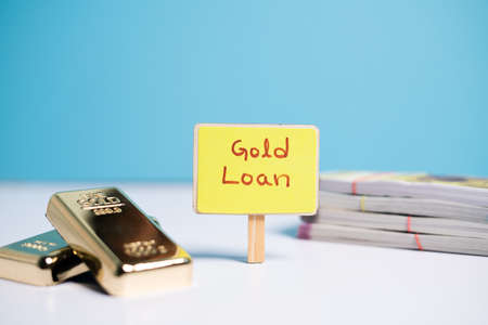 Concept of gold loan showing wiyh Gold loan sign board with Gold bars and currency notes on tableの写真素材