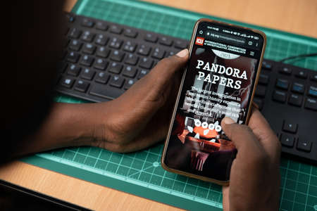 Maski, India - October,16, 2022 : Shoulder shot of man reading Pandora papers website ICIJ about recent exposes related to Money and financial system.のeditorial素材