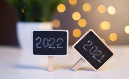 Closeup shot of new year 2022 sign board with fallen 2021 sign board on decorated background -...