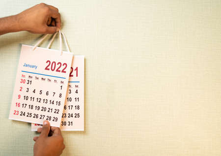 Close up shot of hand replacing 2021 old calendar from 2022 new year calendar on wall - concept of...
