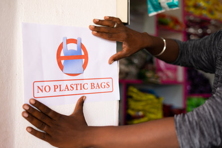 closeup shot of unrecognizable shopkeeper pasting no plastic bag notice on wall - concept to reduce plastic polution and usage at retail storesの写真素材